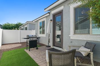 A backyard with a grill and a patio with two chairs